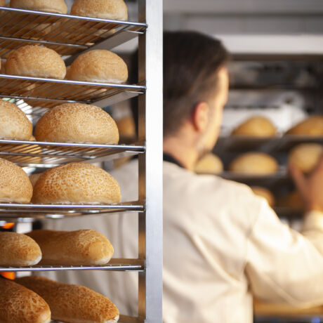 Concentrated man baker standing at bakery near bread
